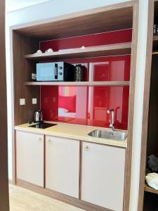 a kitchen with a sink and a red wall at APEC MANDALA CHAMBAY Thanh La Home in Phan Thiet