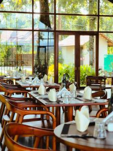 a restaurant with wooden tables and chairs and windows at Sterling Lontano Waterfront Wayanad in Meppādi