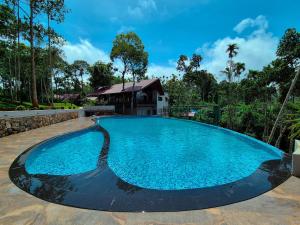 a large blue swimming pool with a house in the background at Sterling Lontano Waterfront Wayanad in Meppādi