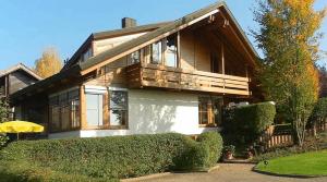 una gran casa de madera con arbustos delante de ella en Gästehaus Helga Scherer, en Ballrechten