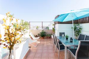 een patio met een tafel en stoelen en een parasol bij San Marcos Apartamentos in Sevilla