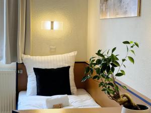 a bed with a black pillow and a potted plant at REGIOHOTEL Salzland Schönebeck in Frohse