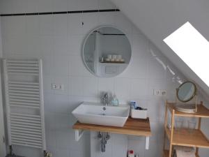 un bagno bianco con lavandino e specchio di Dachgeschosswohnung Seeblick a Tutzing