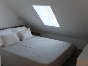 una camera da letto con un letto bianco con una finestra di Dachgeschosswohnung Seeblick a Tutzing