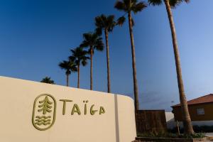 a sign for a hotel with palm trees in the background at TAIGA Almeria Playa in Palomares
