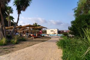 a path next to a swimming pool with umbrellas at TAIGA Almeria Playa in Palomares