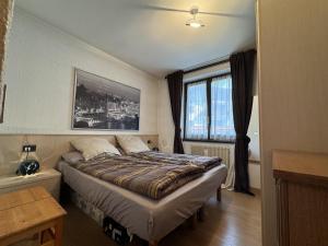 Un dormitorio con una cama con un cuadro en la pared. en 018 Bilocale in centro, Pinzolo, en Pinzolo