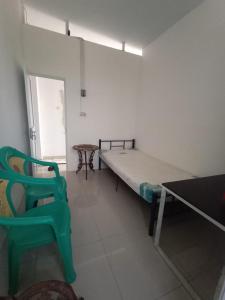 Cette chambre comprend un lit et une chaise verte. dans l'établissement ALMic INN BOGOR, à Caringin