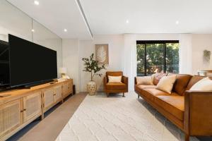 ein Wohnzimmer mit Sofa und Flachbildfernseher in der Unterkunft Vogue charm w light, aspect, AC in Sydney