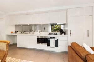 eine Küche mit weißen Schränken und einem Sofa in der Unterkunft Vogue charm w light, aspect, AC in Sydney