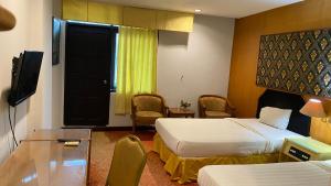 a hotel room with two beds and a television at Mas graha hotel in Pekanbaru
