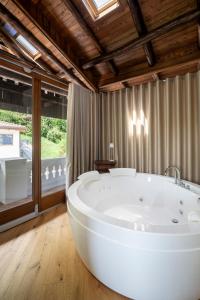 - dużą białą wannę w pokoju z oknem w obiekcie La Portineria Luxury B&B w mieście Piancogno