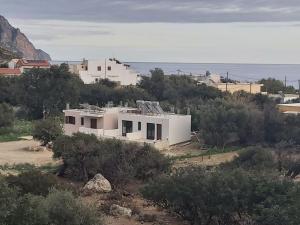 a white house on top of a hill with the ocean at Talos in Sougia