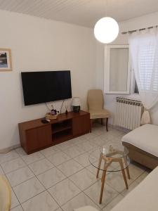 a living room with a flat screen tv and a couch at Apartmani Šprljan in Vodice