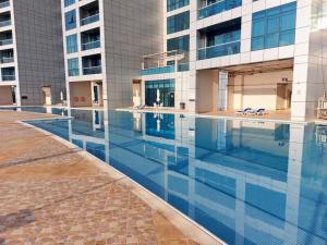 a large swimming pool in front of a building at Luxury Corniche Residence 2 BHK pool gym wifi sea front in Ajman 
