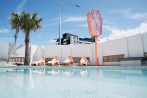 a group of pink chairs sitting next to a swimming pool at The Mysa Motel in Gold Coast
