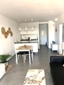a living room and kitchen with a white table and chairs at Ground floor apartment with pool, next to the beach in Costa Teguise