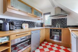 eine Küche mit Holzschränken und einem rot-weiß karierten Boden in der Unterkunft Le Cottage à 10min de Disneyland Paris in Chalifert + 43 Fotos