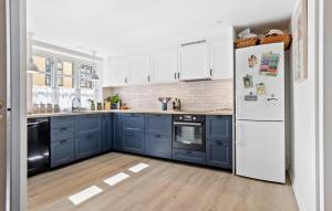 a kitchen with blue cabinets and a white refrigerator at 3 Bedroom Lovely Home In Faaborg in Fåborg