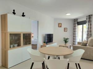 マラガにある1º Línea de playa con piscina panorámica & parkingのリビングルーム(テーブル、白い椅子付)