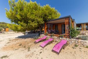 迪斯诺Paradisum sub sole的房子前的沙滩上摆放着一组粉色躺椅