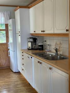 a kitchen with white cabinets and a sink and a refrigerator at Hus med panorama utsikt in Måløy +14 photos