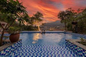 a large swimming pool with a sunset in the background at Nhà Ven Hồ Đồng Đò, Minh Trí, Sóc Sơn, Hà Nội in Hanoi