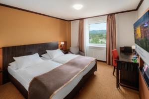 Una habitación de hotel con una cama y un televisor de pantalla plana. en Trans World Hotel Donauwelle, en Linz