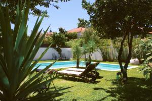 a backyard with a swimming pool with a chaise lounger and a pool at Vila Vale Guest House - Surf & Yoga in Charneca
