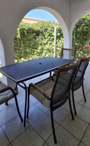 einen schwarzen Tisch und zwei Stühle auf einer Terrasse in der Unterkunft Kuća za odmor-Val in Vir