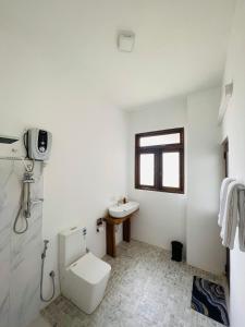 a white bathroom with a toilet and a sink at The Lotus Villa Sigiriya in Sigiriya