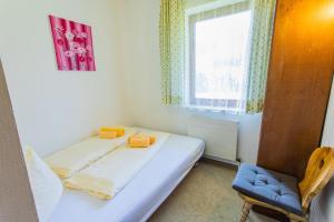 a bedroom with a bed and a chair and a window at Huberhof 5 by Alpenidyll Apartments in Rohrmoos