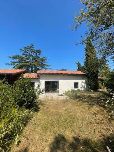 a white house with trees in front of it at Chambre d'hôte in Monflanquin +1 photo