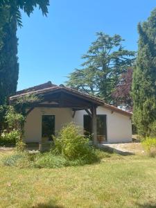a small white house in a yard with trees at Chambre d'hôte in Monflanquin