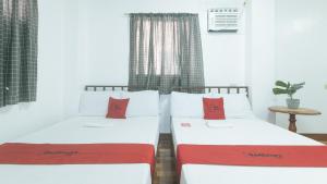 two beds with red pillows in a room at RedDoorz at Joel's Apartelle in Calaboso