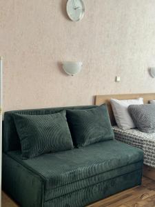 a green couch in a living room with a clock on the wall at Студия Sea Breeze in Sveti Vlas