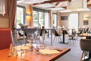 a table in a restaurant with wine glasses on it at Logis Hotel Restaurant Au Chêne Vert, Saint-Brieuc in Plérin