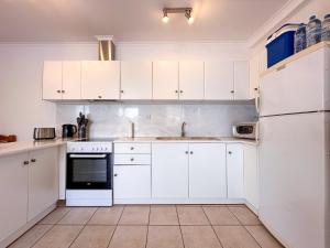 a white kitchen with white cabinets and appliances at Villa Nitsa in Vathi