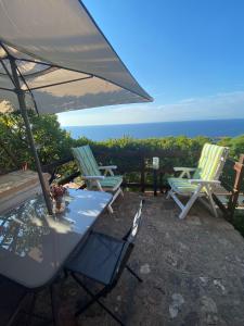 コスタ・パラディーゾにあるappartamento con incantevole vistaの椅子2脚、テーブル1台(パラソル付)