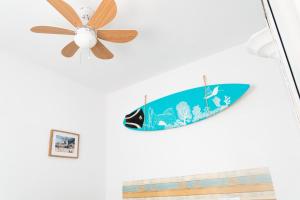 a surfboard hanging on a wall next to a ceiling fan at Daydream Medano Coliving in El Médano