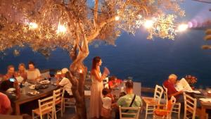 a group of people sitting at tables in a restaurant at Villetta IRENULLA in Posidhonía