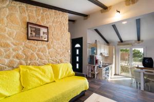ein Wohnzimmer mit einem gelben Sofa und einer Steinmauer in der Unterkunft Kuća za odmor R&A in Podstrana