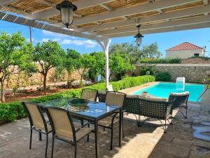 a patio with a table and chairs and a pool at Villa Lida Spetses - Private Pool in Spetses
