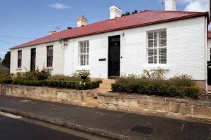 ein weißes Haus mit rotem Dach auf einer Straße in der Unterkunft Tamara Cottage Historic Warmth in Hobart