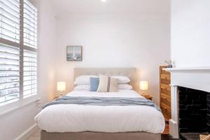 ein weißes Schlafzimmer mit einem großen Bett und einem Kamin in der Unterkunft Tamara Cottage Historic Warmth in Hobart
