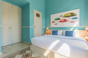 a bedroom with a large white bed with umbrellas on the wall at SAYA La Villa in Mar Mikhael in Beirut