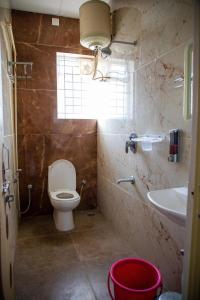 a bathroom with a toilet and a sink and a window at Serenity Stay Inn in Bengaluru
