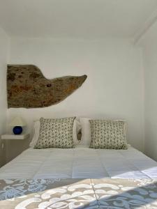 a white bed with pillows and a fish on the wall at A casa dos avós in Abrantes +22 photos