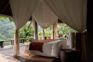 a bedroom with a bed with curtains and a balcony at Buahan, a Banyan Tree Escape in Payangan