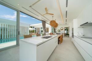 ラワイビーチにあるTropical Brand New 4BR Pool Villa Mina, just 5 min Drive from Naiharnのキッチン(白いカウンタートップ、大きな窓付)